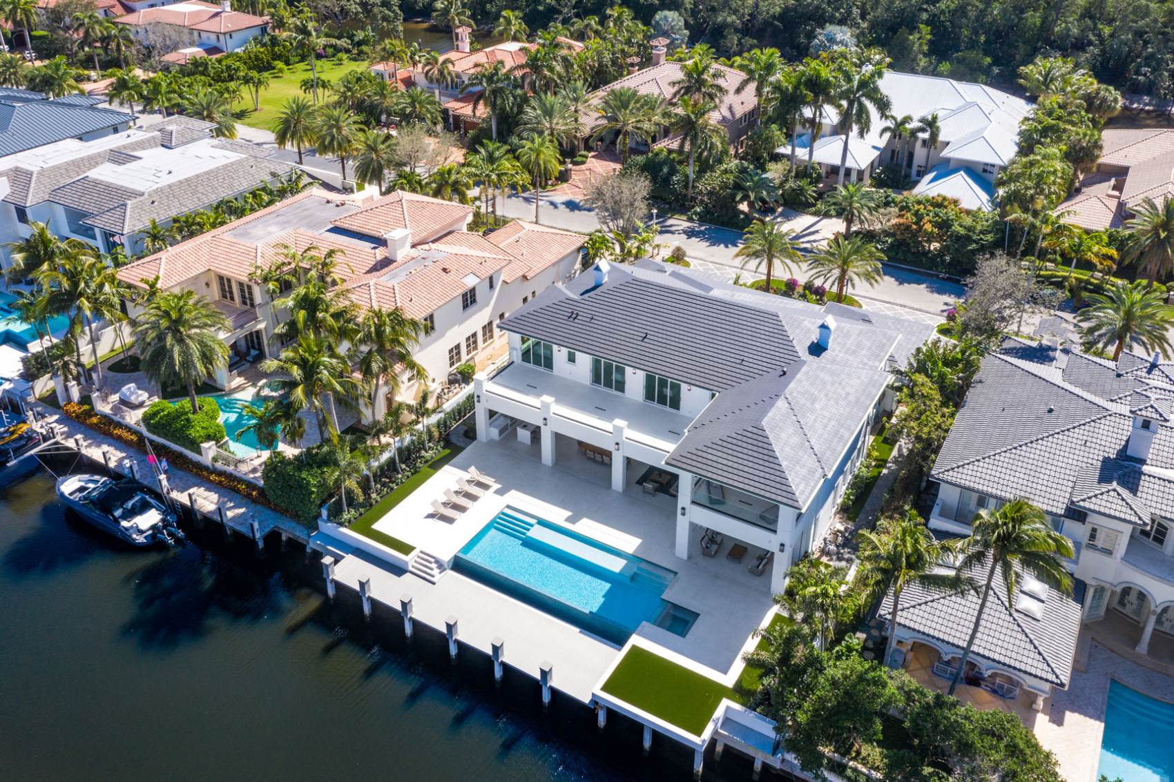A large white house with pool and dock.