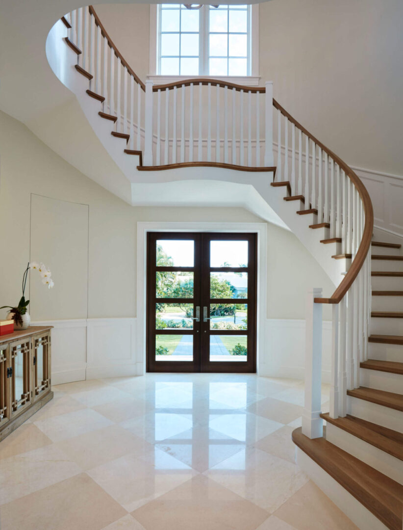 A large white foyer with stairs and a door.