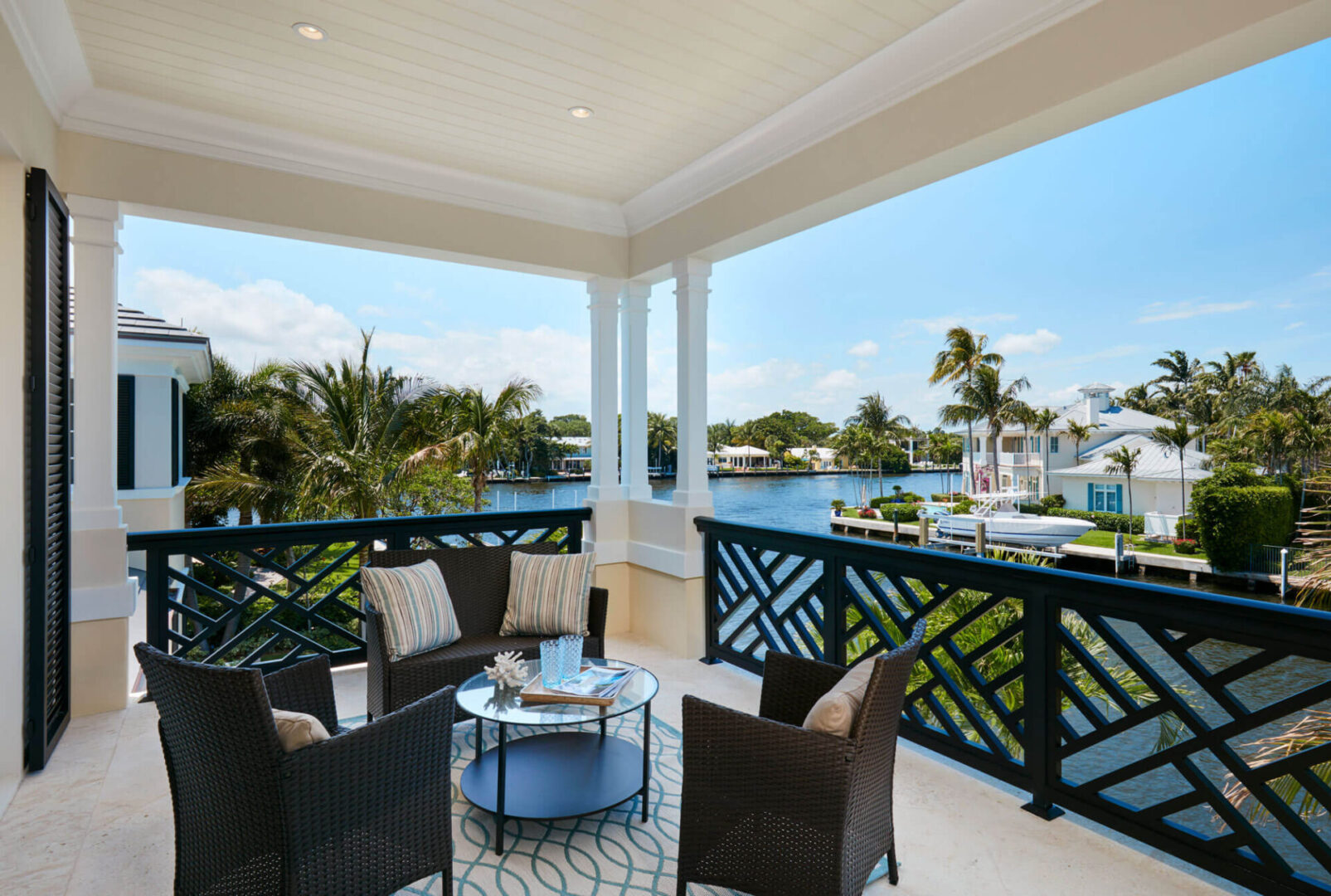A balcony with chairs and tables overlooking the water.