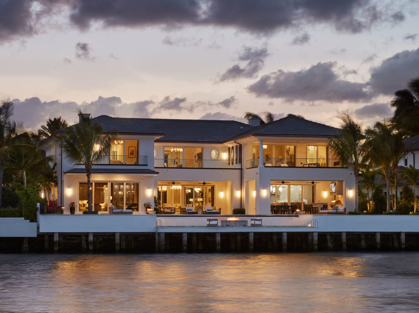 A large house on the water at dusk.