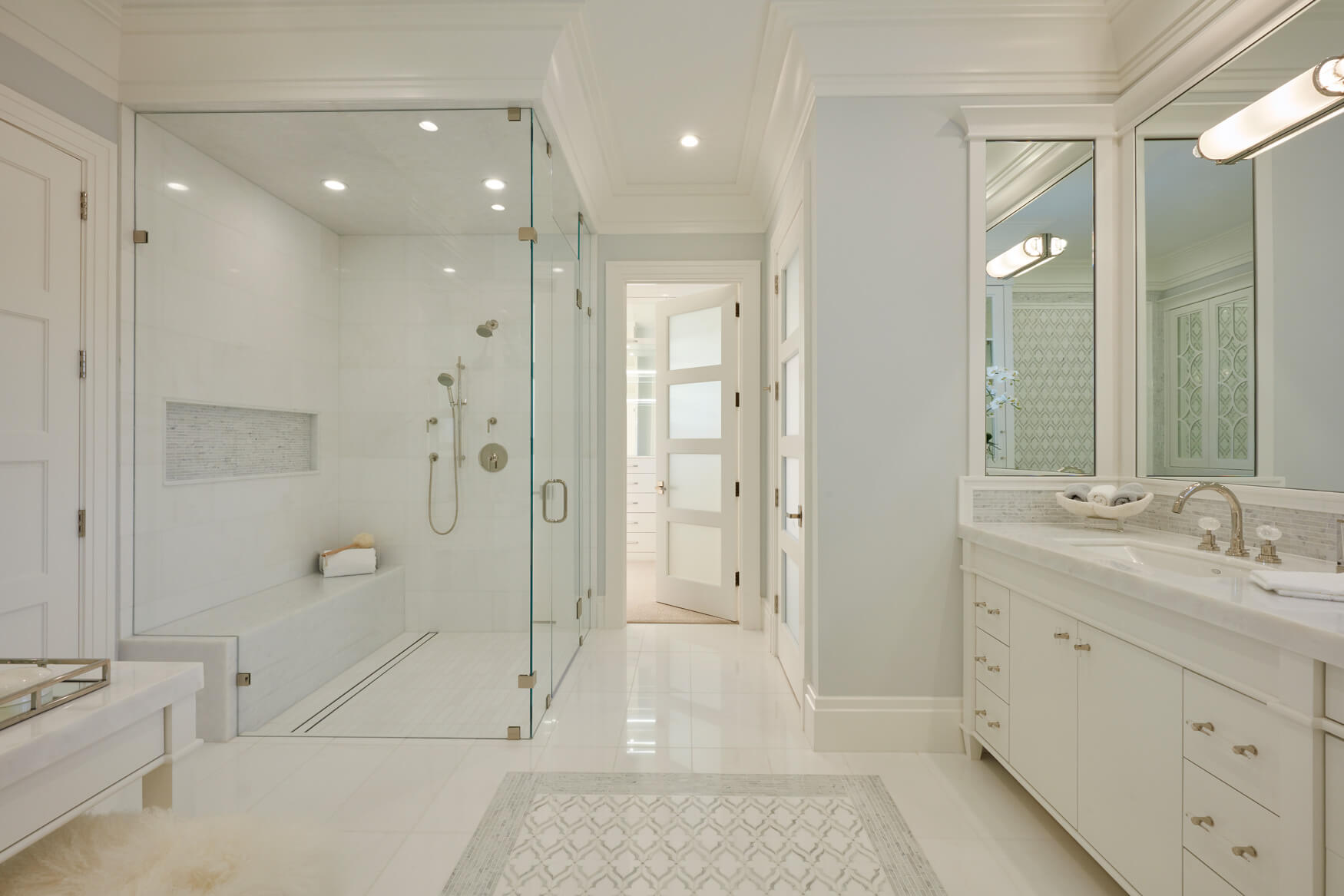 A white bathroom with a walk in shower and a large mirror.