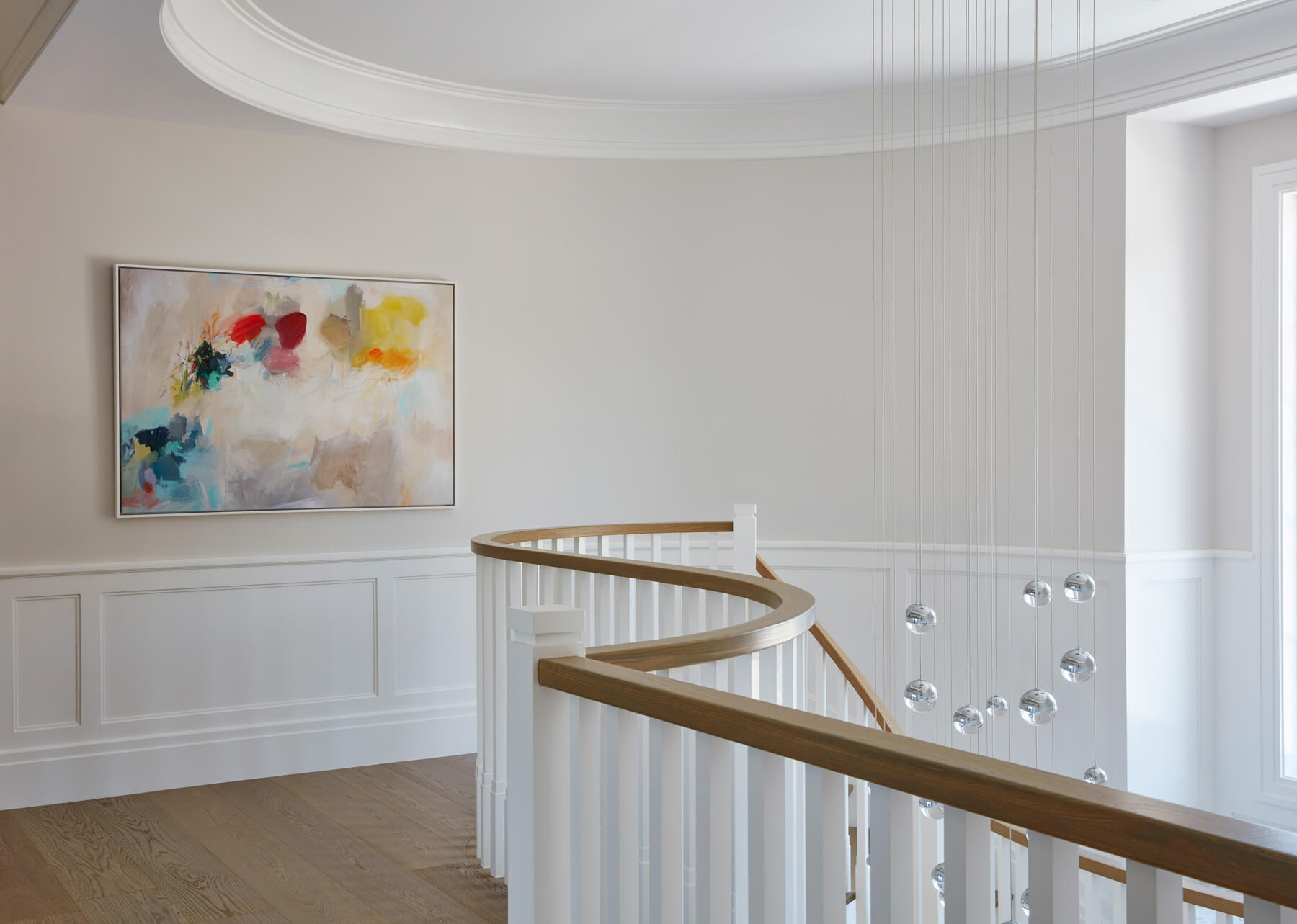 A white staircase with a painting hanging on the wall.