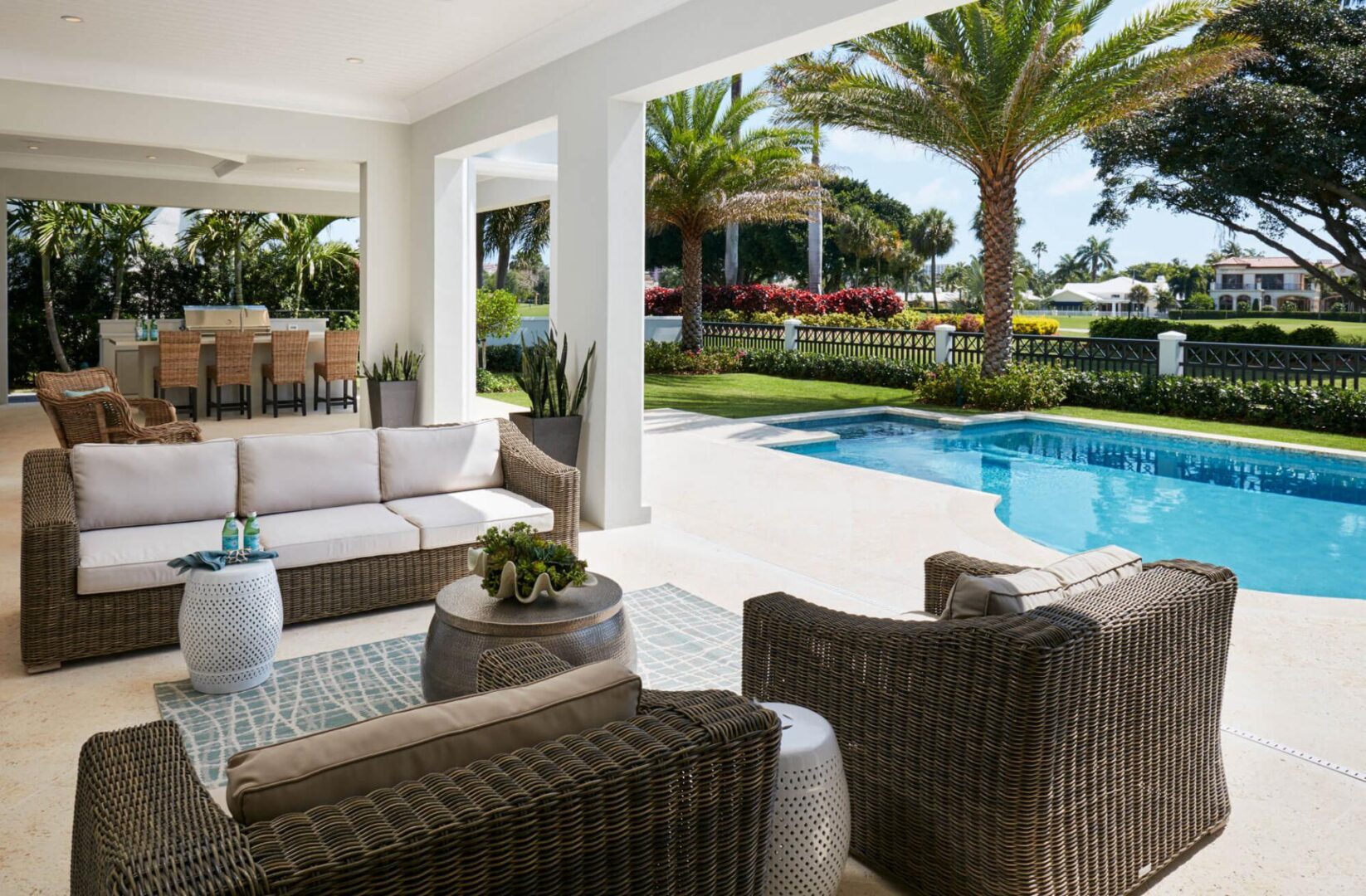 A patio with furniture and pool in the background.