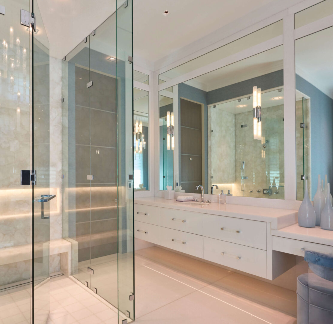 A bathroom with a glass shower door and white cabinets.