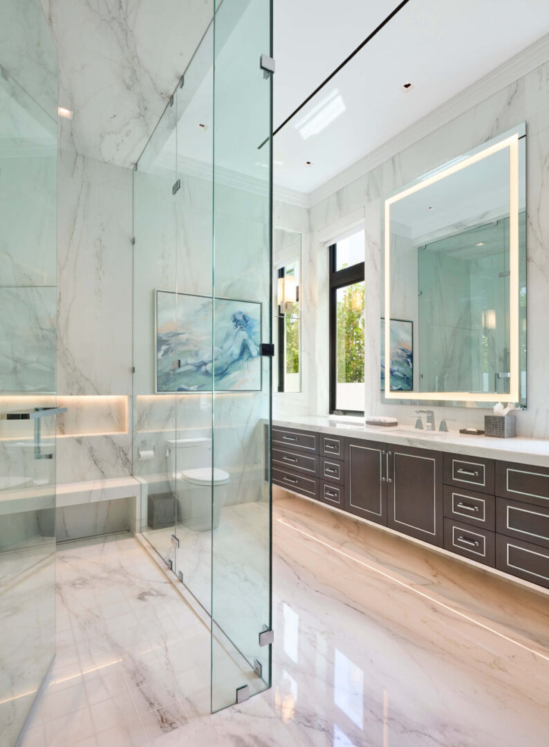 A bathroom with marble walls and floors, and a large mirror.