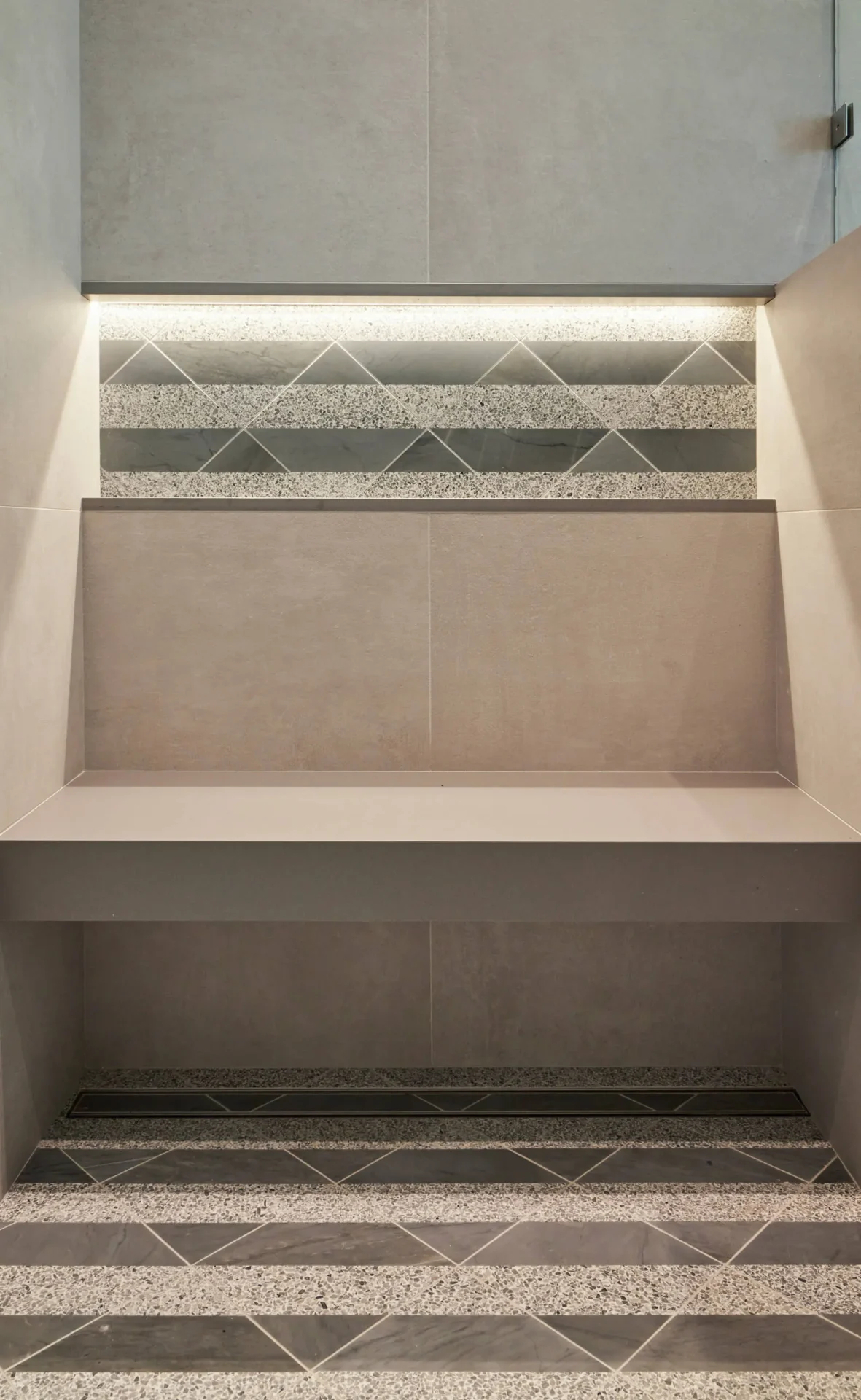 A bathroom with a tiled wall and a shelf
