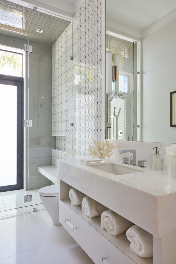A bathroom with white tile and glass shower.