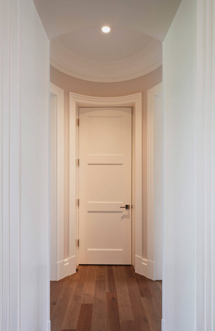 A door way with two white doors and a wooden floor.