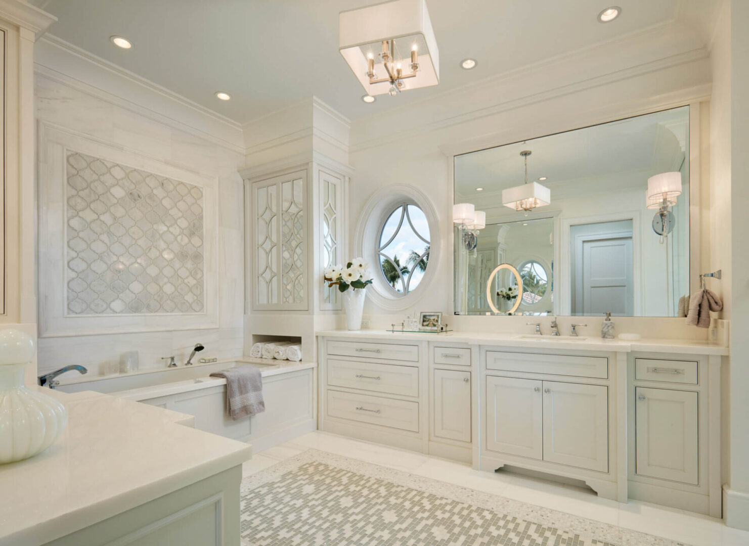 A bathroom with white cabinets and a large mirror.
