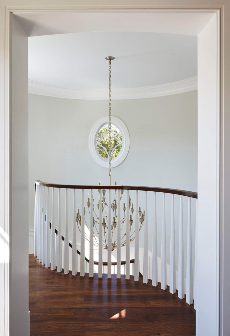 A chandelier hanging from the ceiling in front of a white staircase.