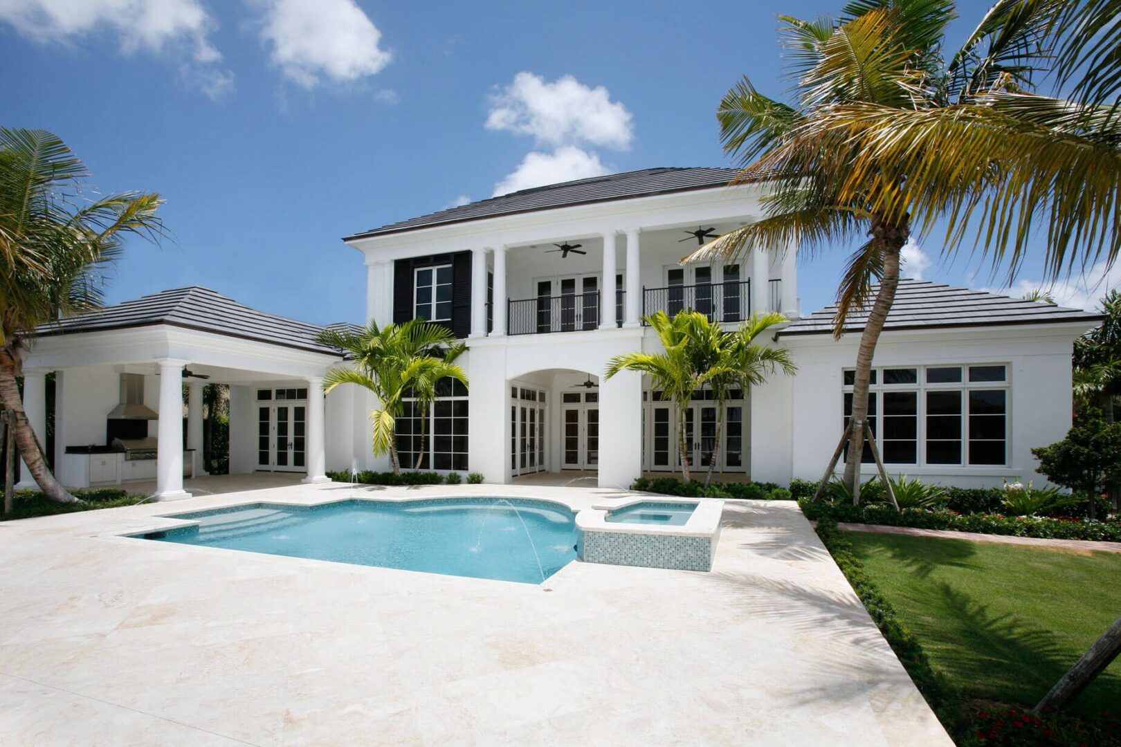 A large white house with pool and palm trees.