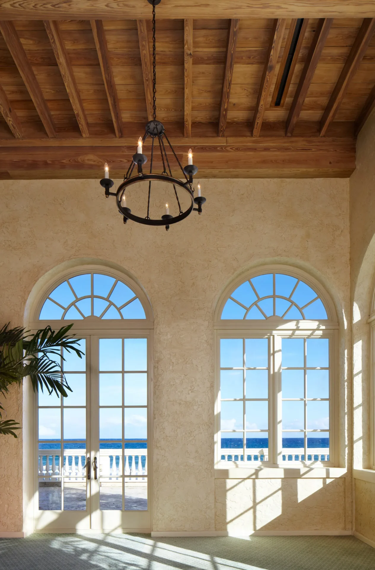 A chandelier hangs above two windows in the center of an indoor room.