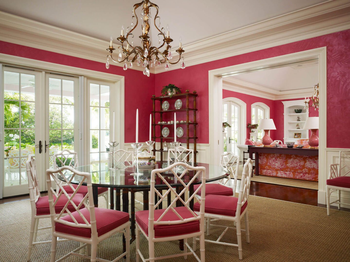 A dining room with pink walls and white furniture.