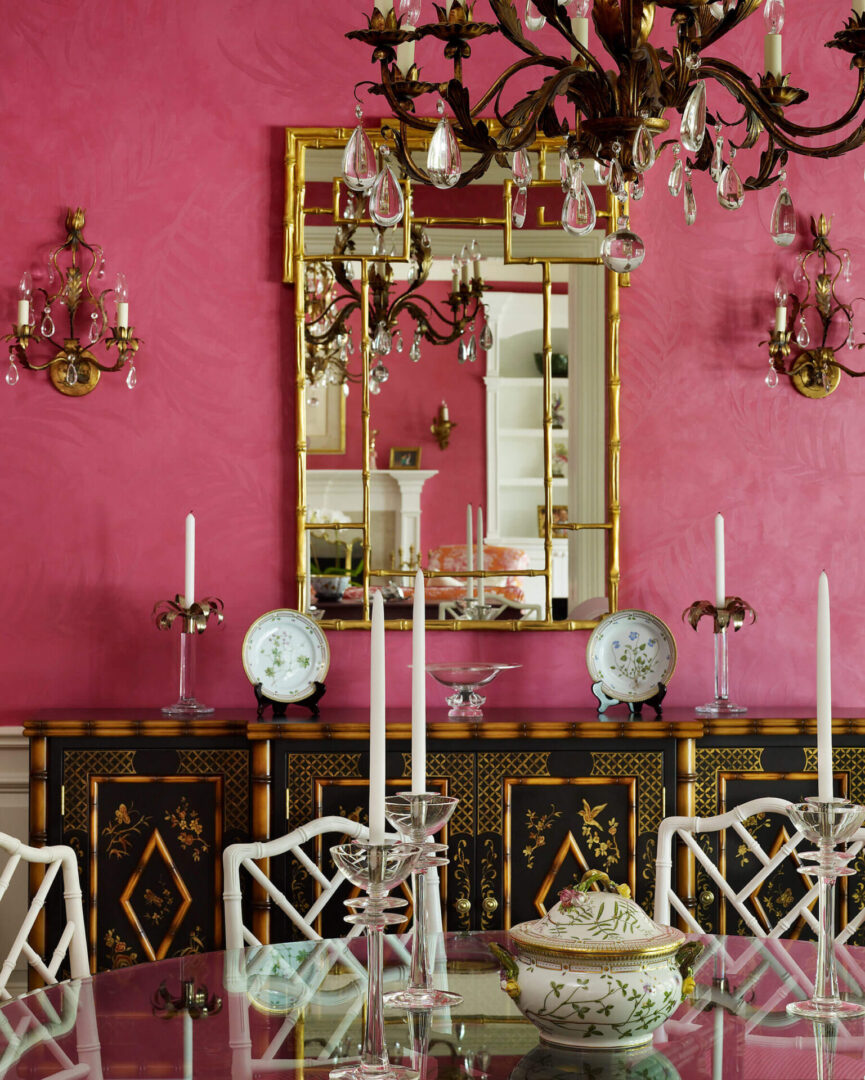 A dining room with pink walls and white chairs.