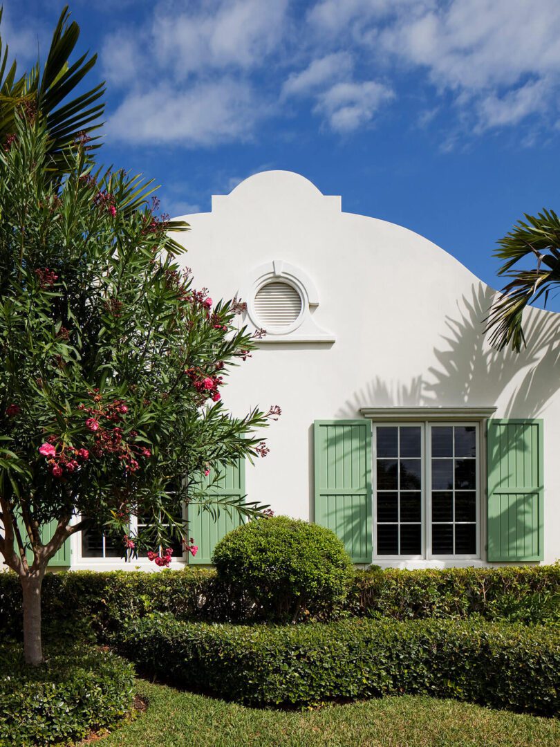 A white building with green shutters and windows.