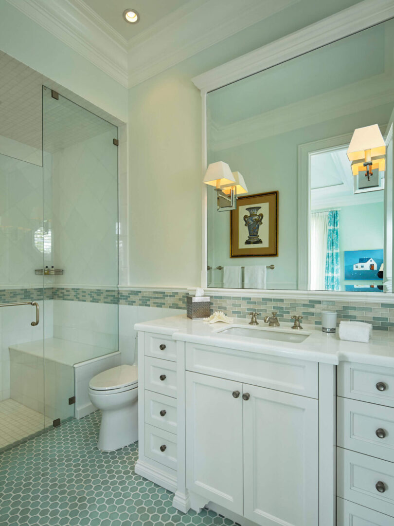 A bathroom with white cabinets and green tile.