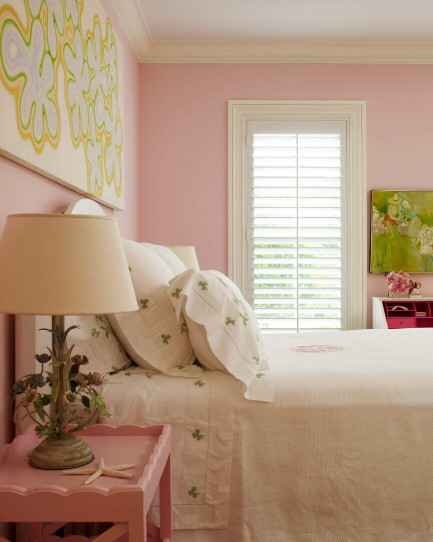 A bedroom with pink walls and white bedding.