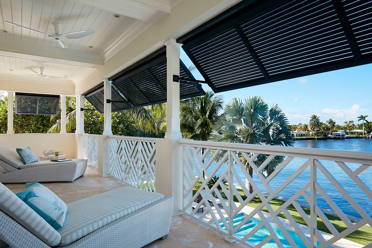 A balcony with a view of the water and palm trees.