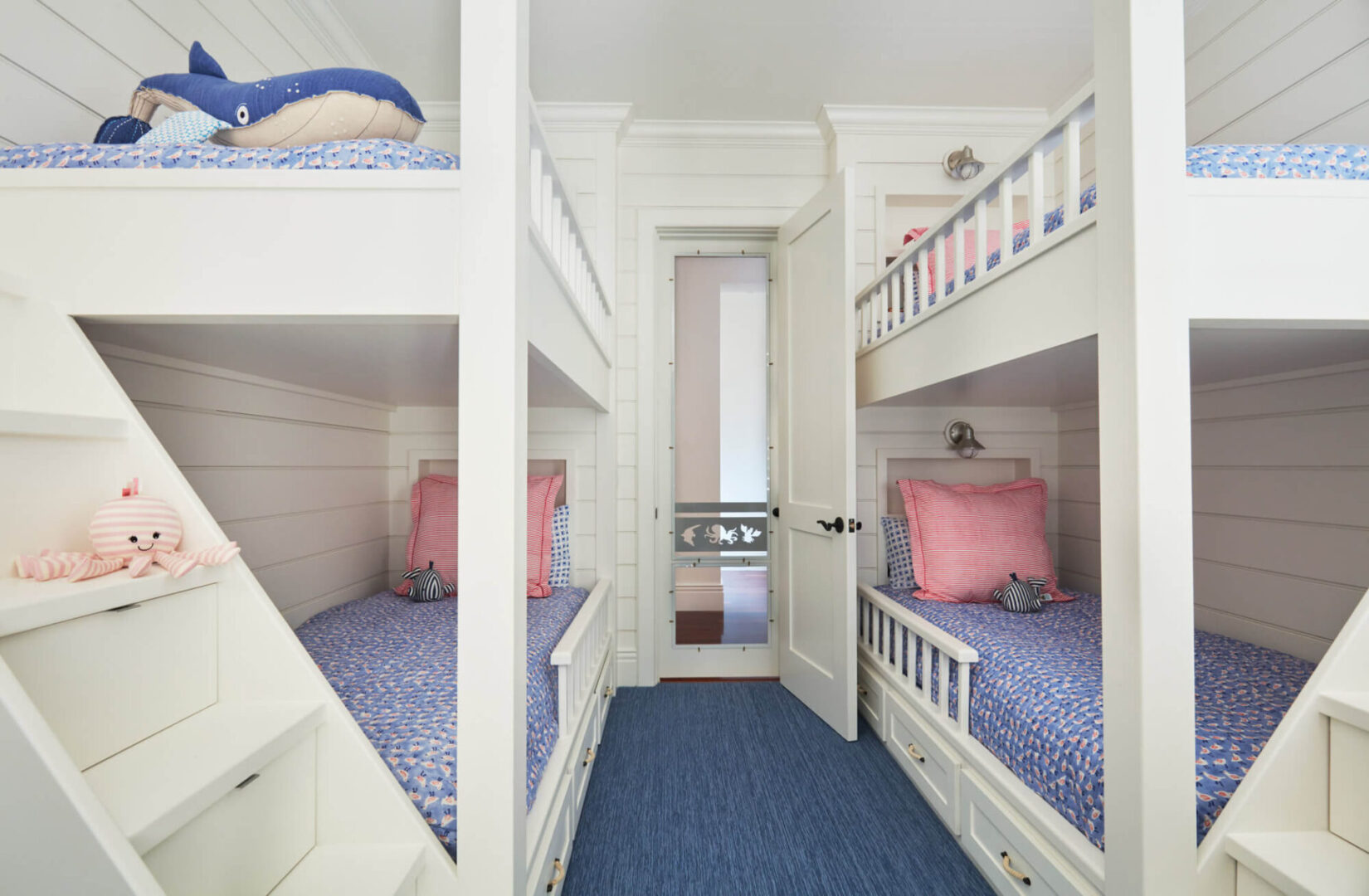 A room with bunk beds and stairs leading to the second floor.