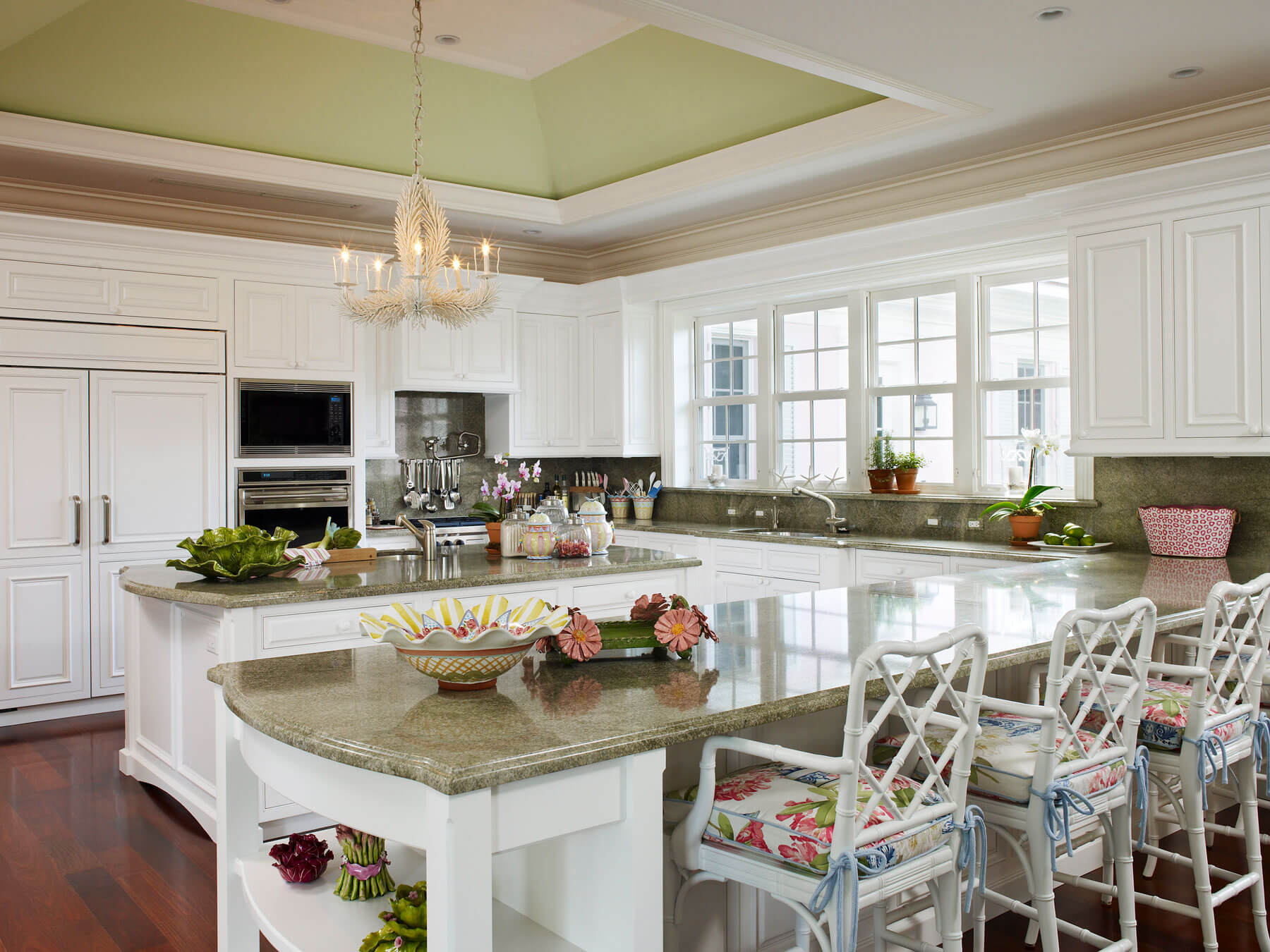 A kitchen with white cabinets and green counter tops.