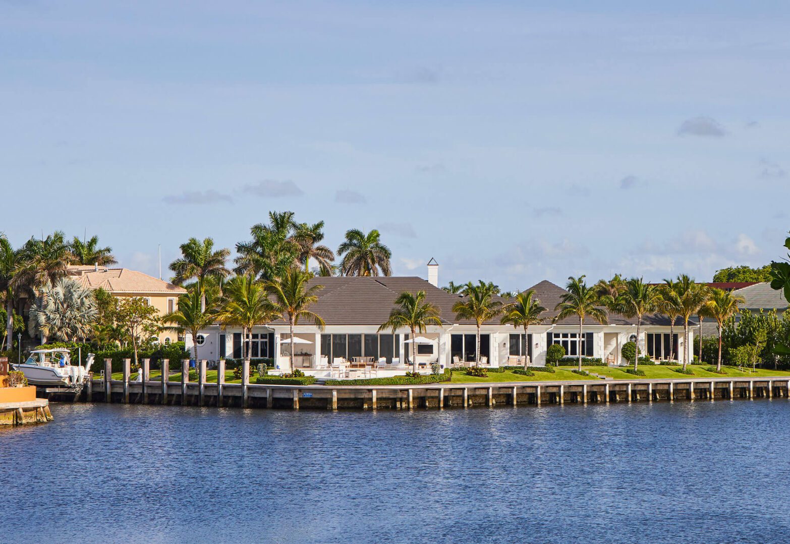 A large house on the water with palm trees.