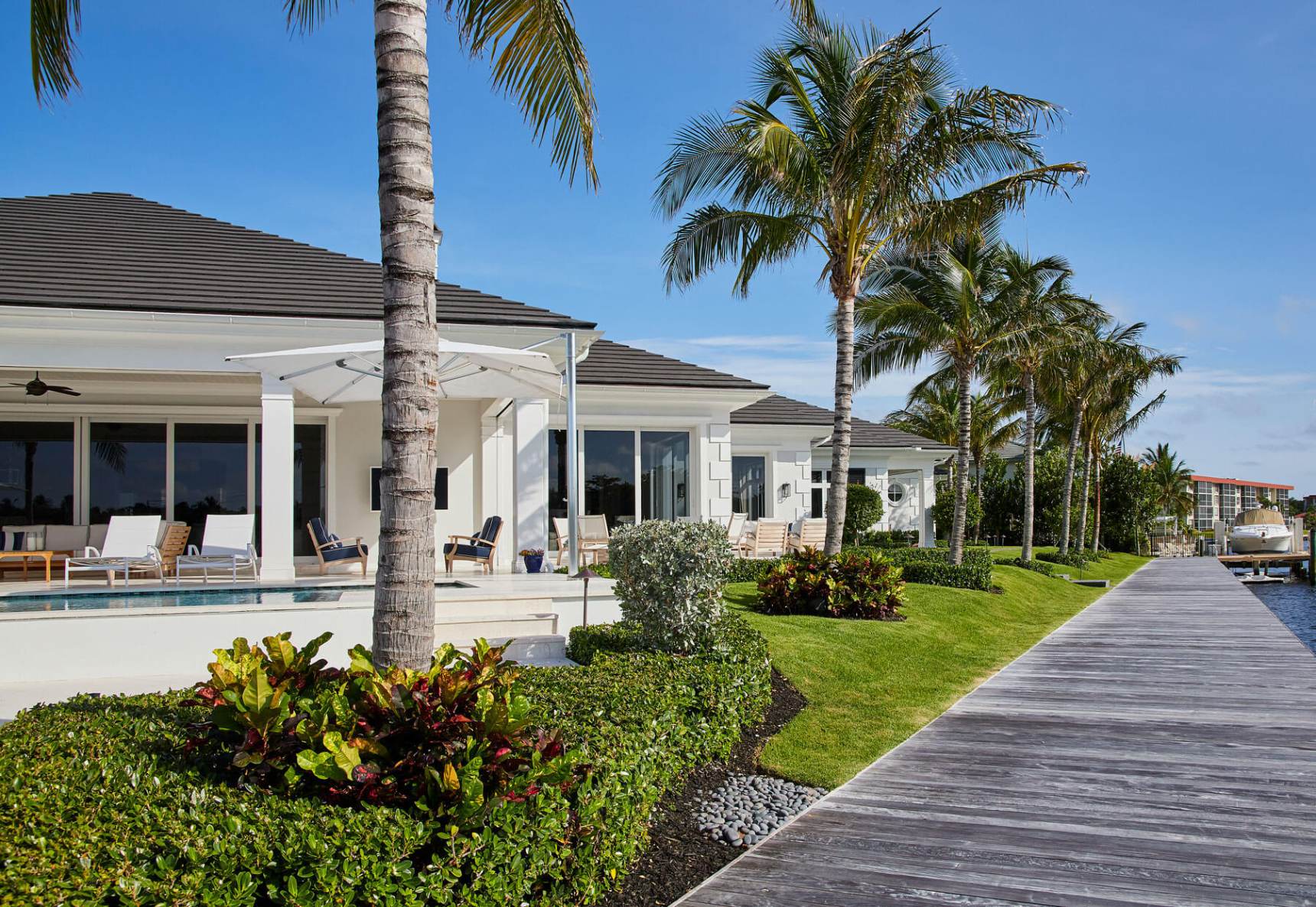 A white house with palm trees and a wooden walkway.