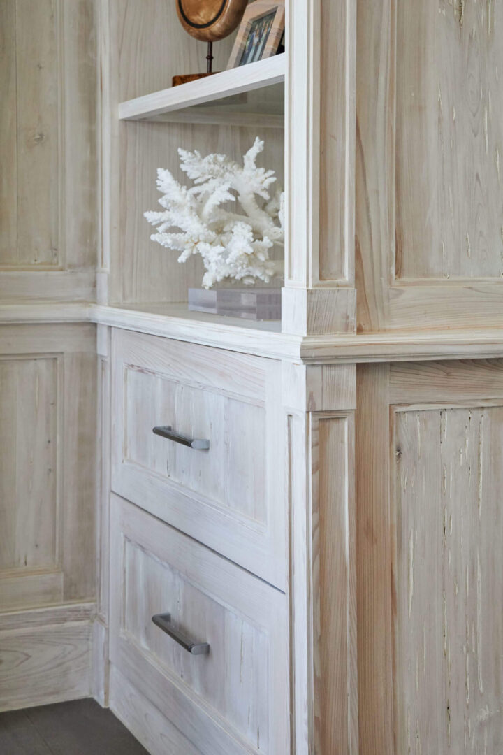 A white cabinet with two drawers and a glass door.