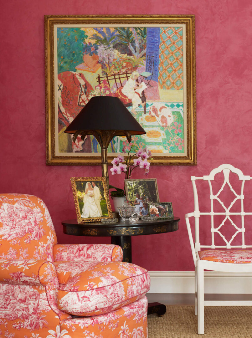 A living room with pink walls and a painting on the wall.