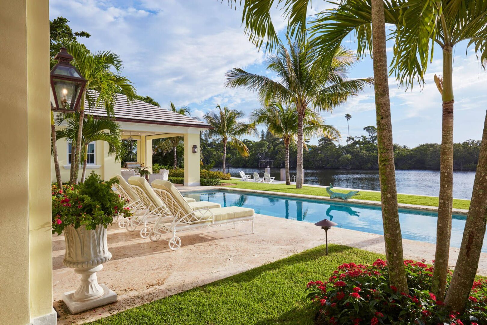 A pool with a gazebo and palm trees in the background.