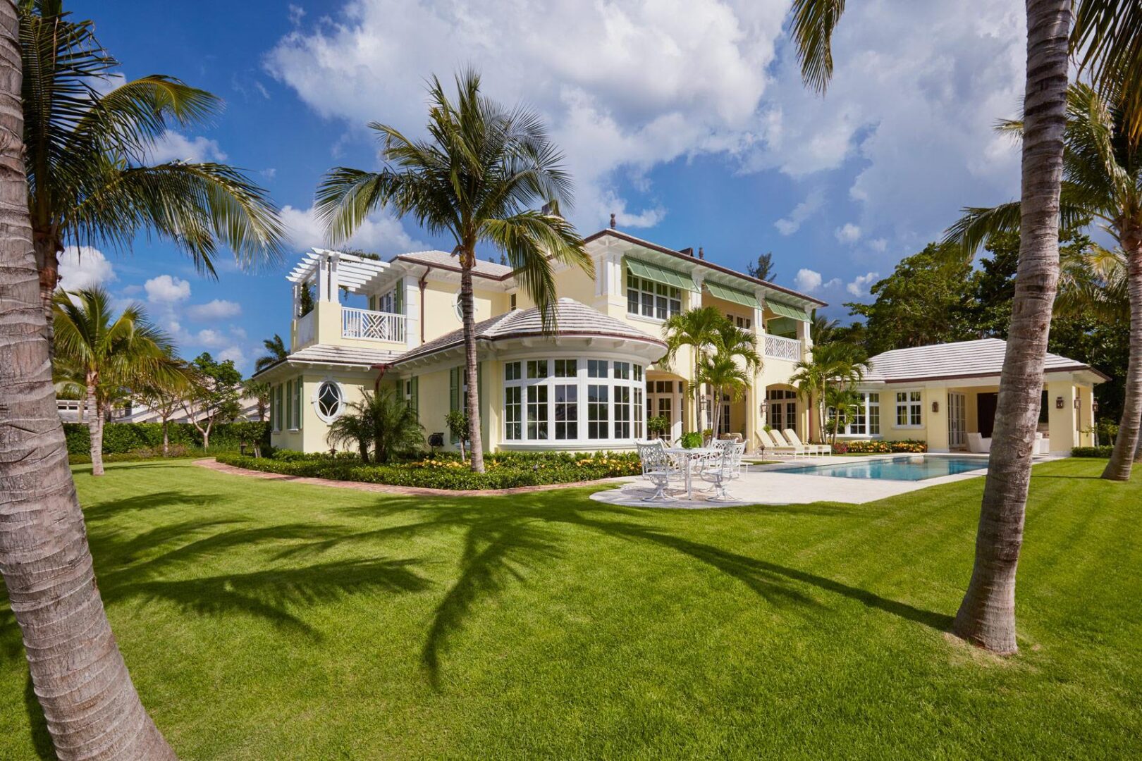 A large white house with palm trees in the background.