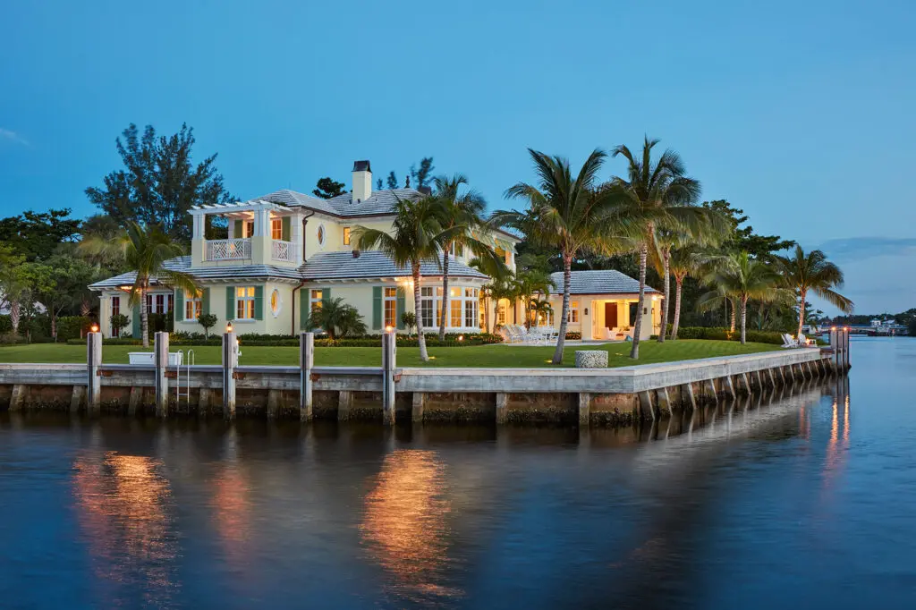 A large house on the water with palm trees.
