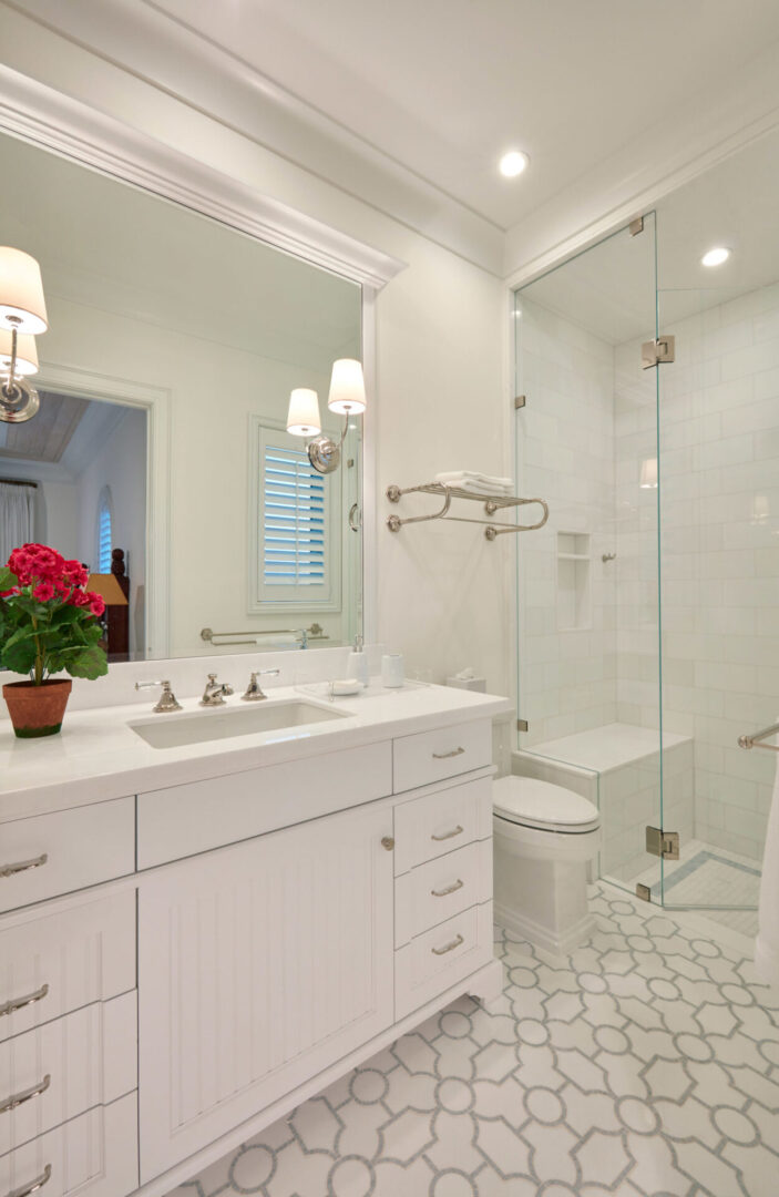A bathroom with white cabinets and a glass shower door.