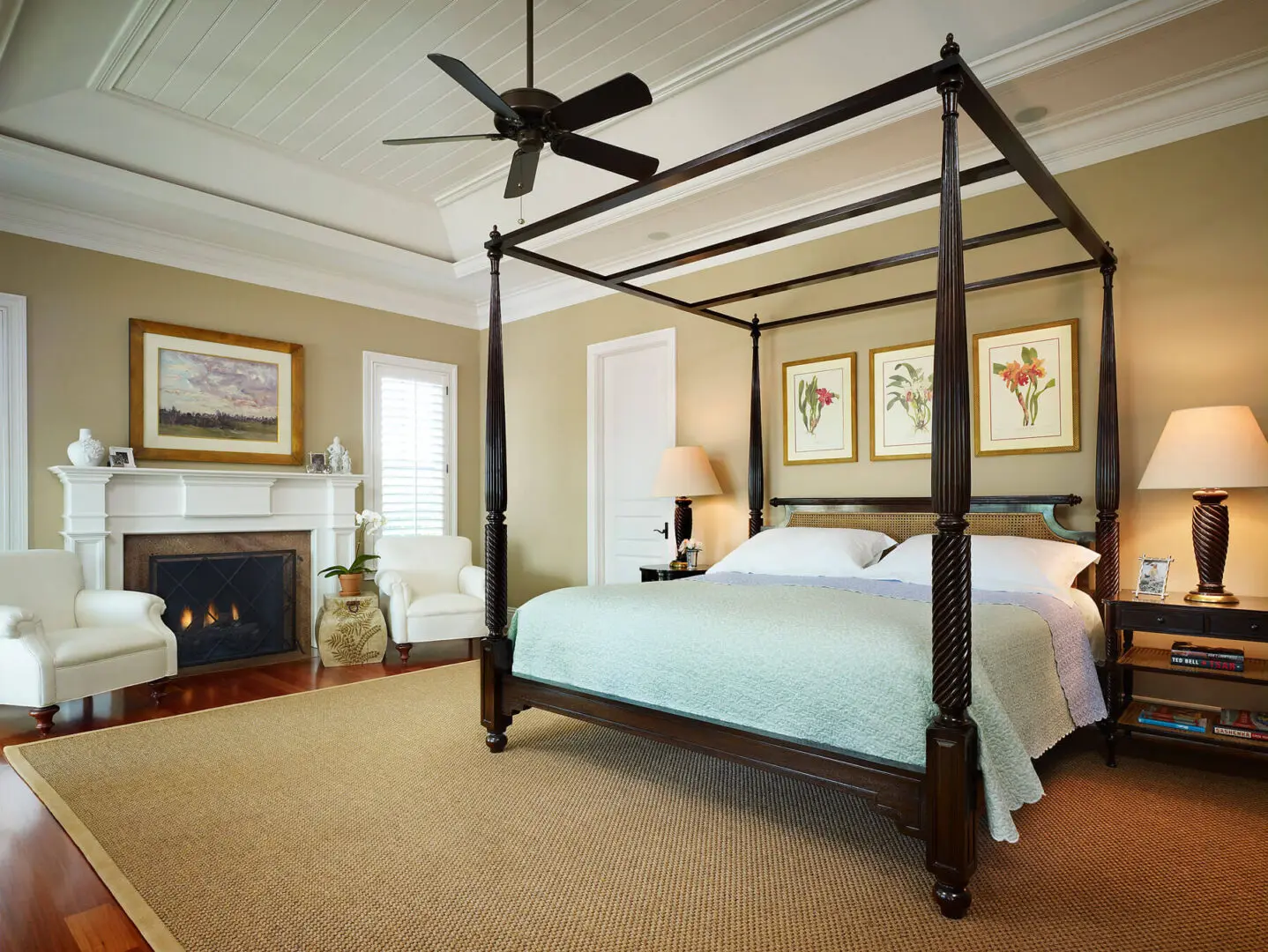 A bedroom with a bed, fireplace and ceiling fan.