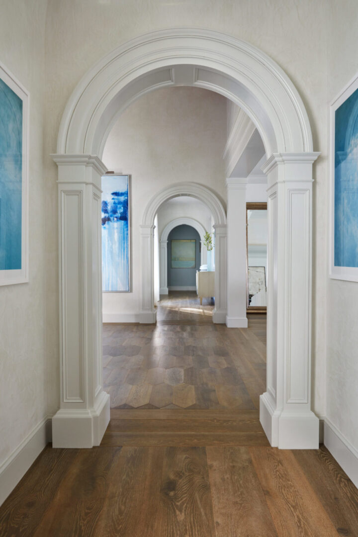 A hallway with two arches and two paintings on the wall.