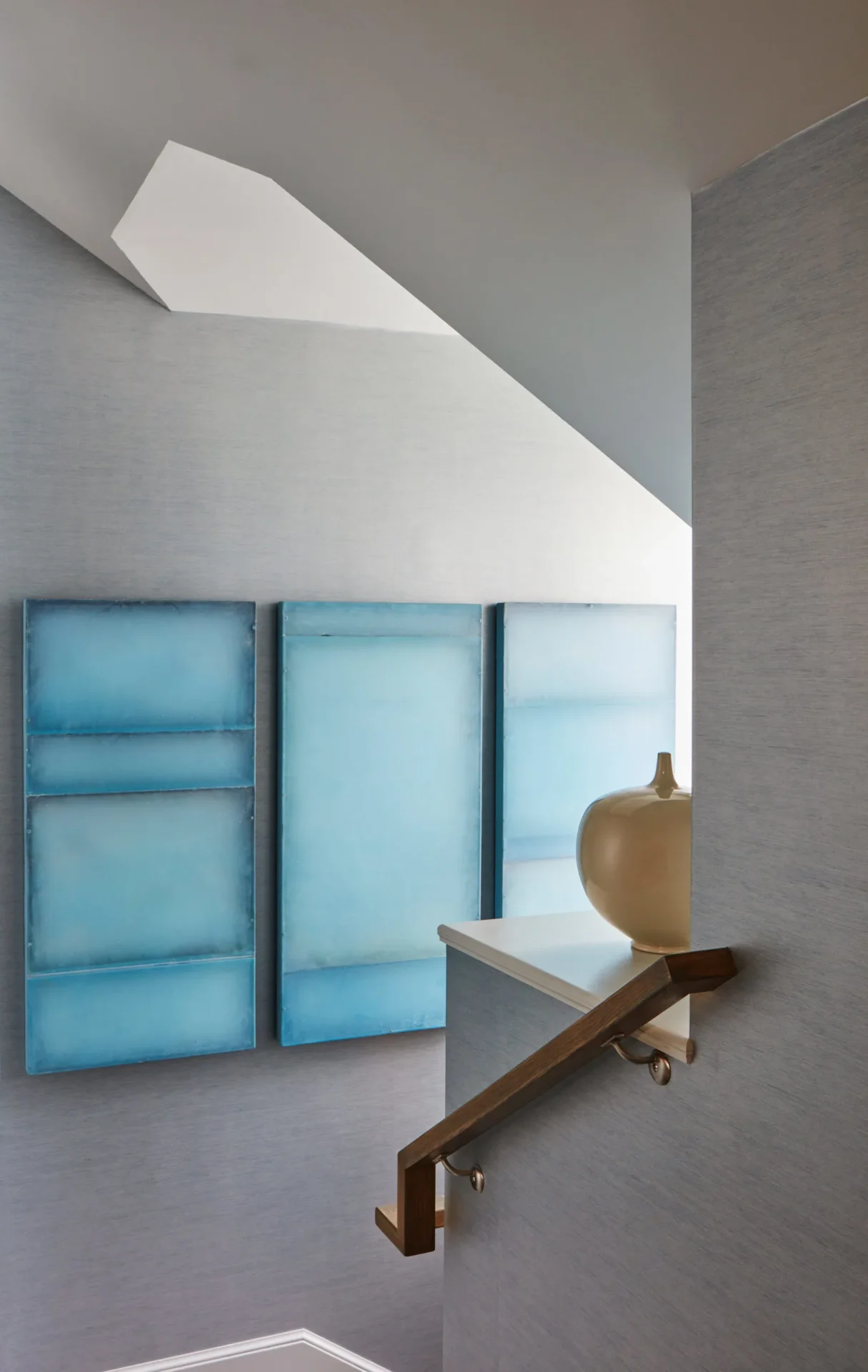 A wall with three blue panels and a vase on the ledge.
