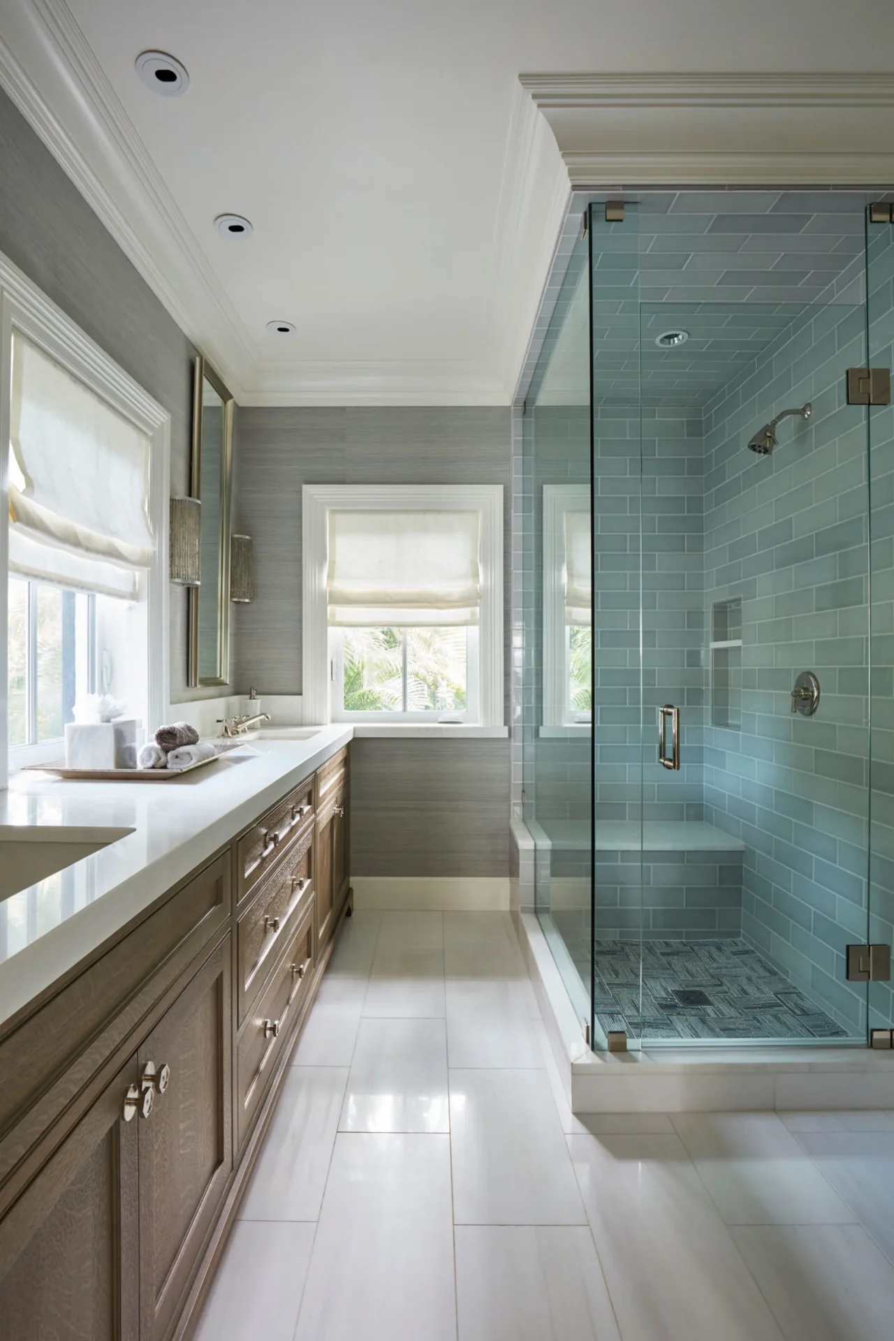 A bathroom with a large glass shower and marble counter.