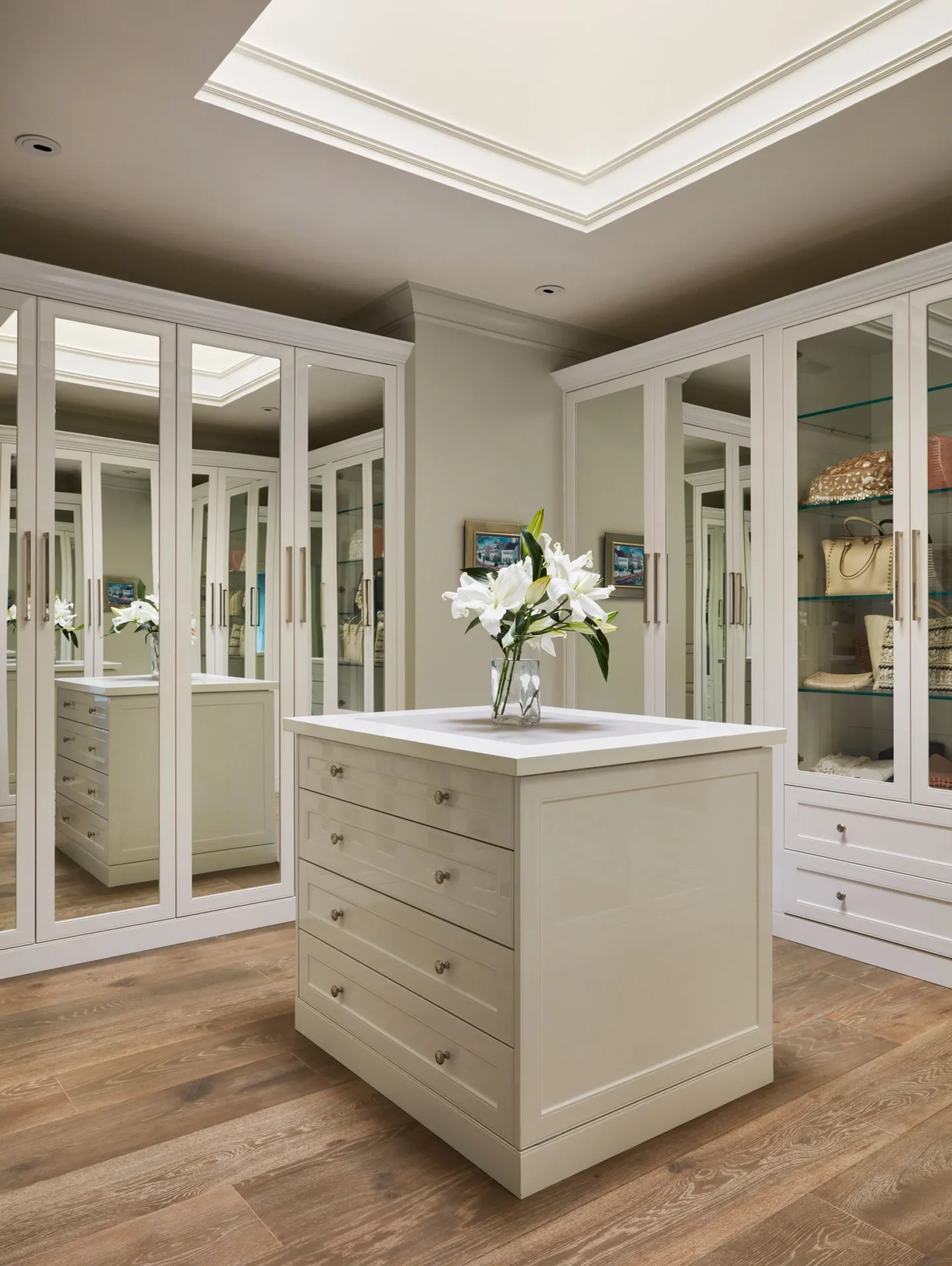 A large white closet with many mirrors and drawers.