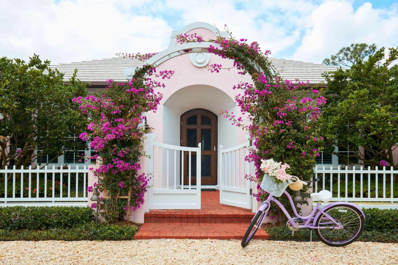 A bicycle parked in front of a house with flowers on the steps.