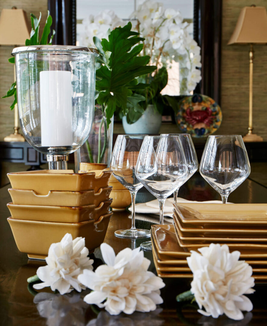 A table with plates, glasses and flowers on it.