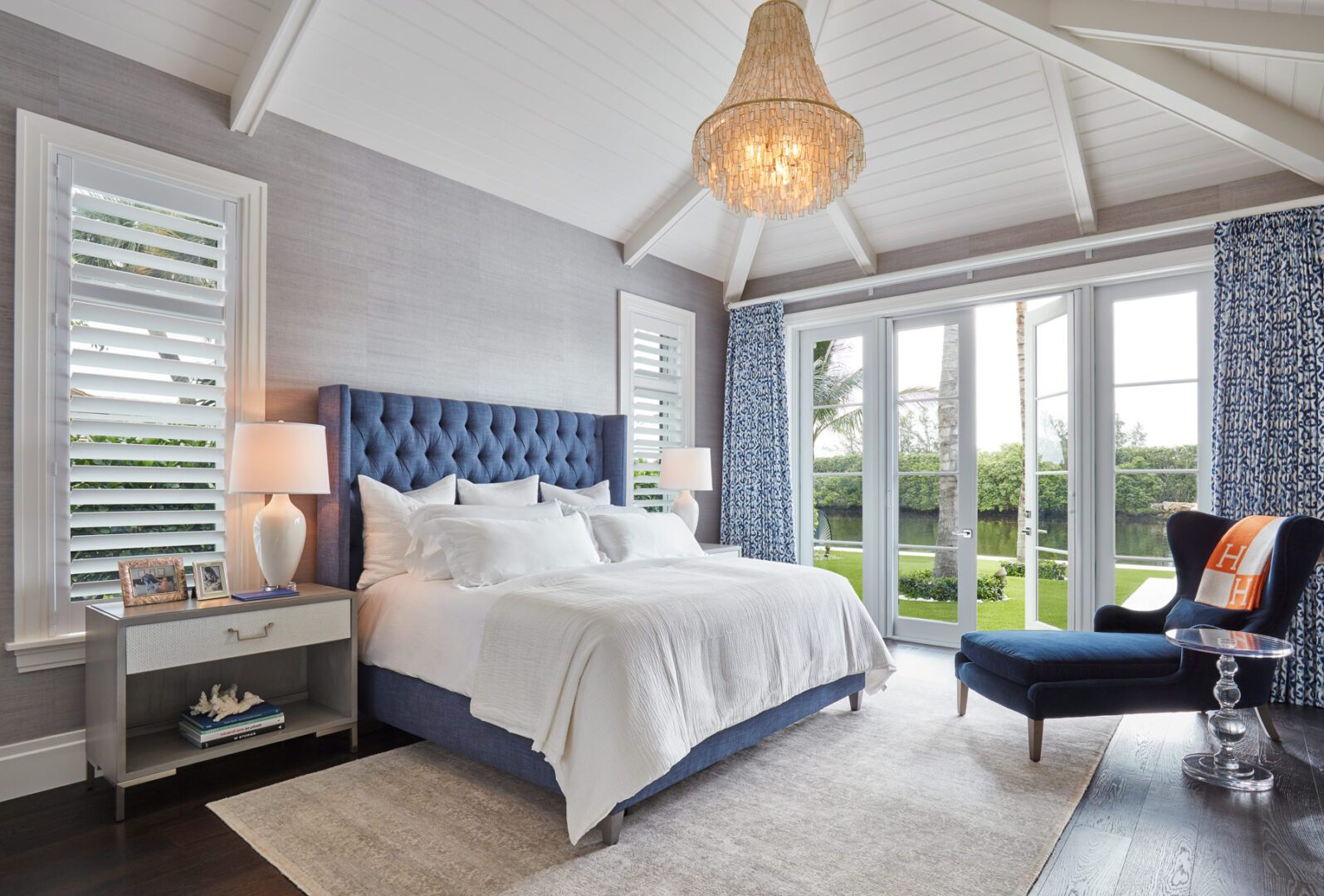 A bedroom with blue tufted headboard and white walls.