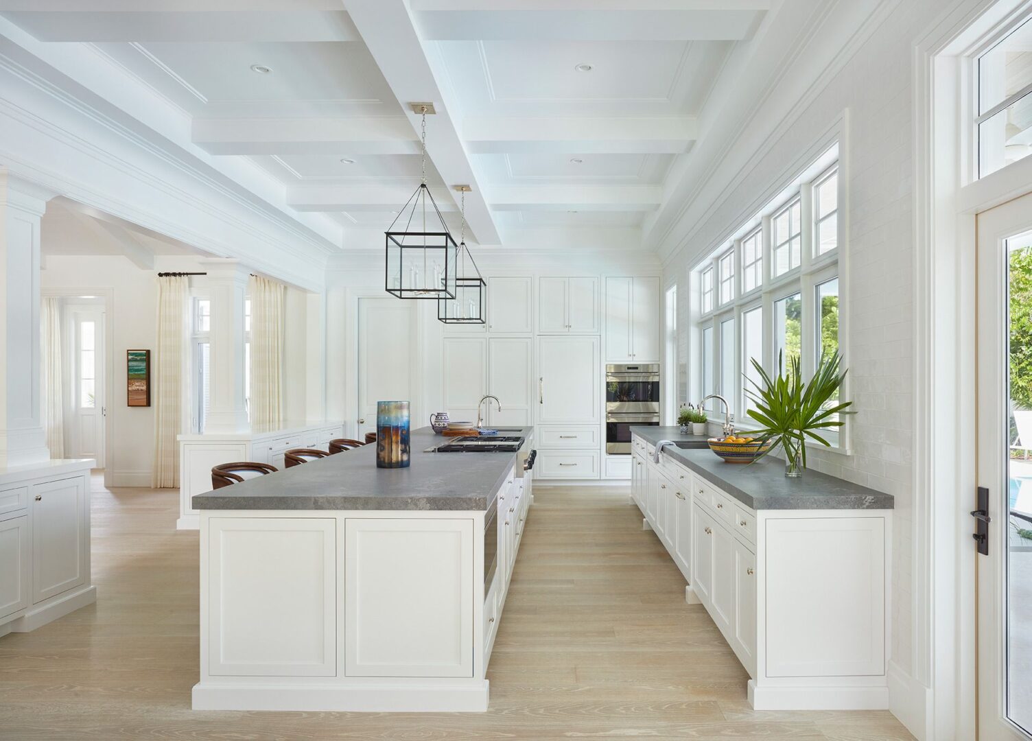 A large kitchen with white cabinets and black counter tops.