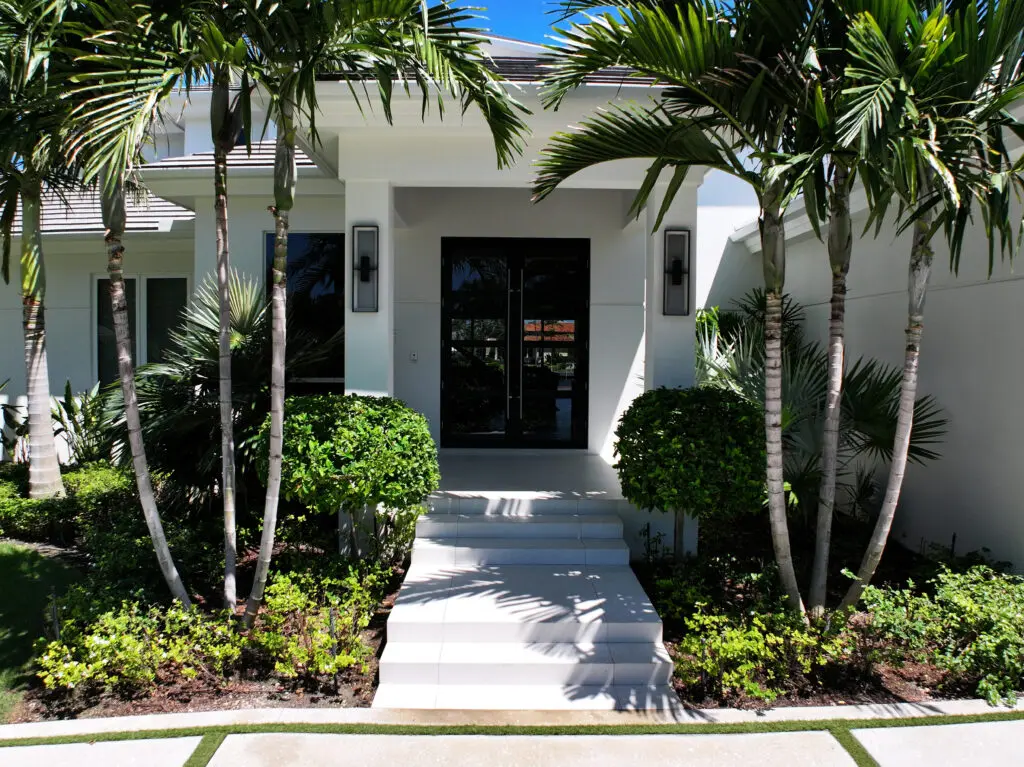 White house entry with palm trees and steps.