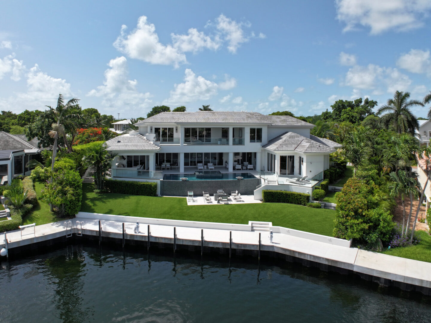 White waterfront home with pool and dock.