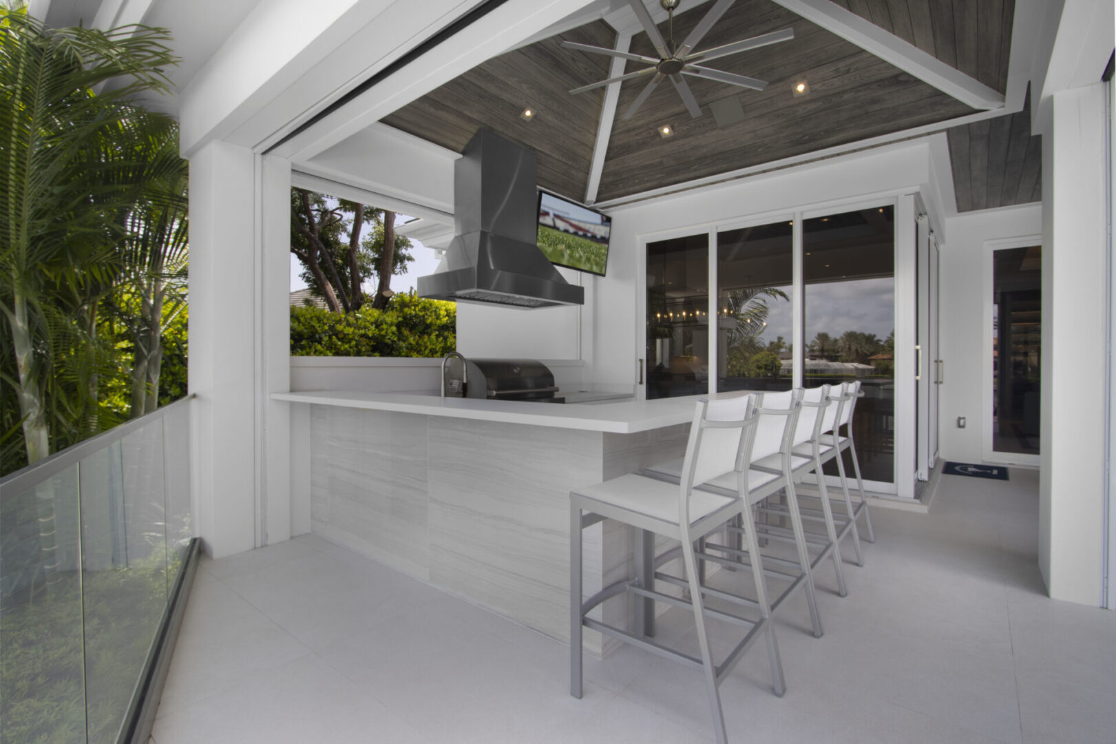 Outdoor kitchen with bar stools and a grill.