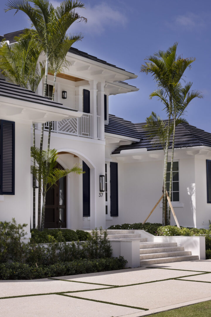 White house with palm trees and steps.