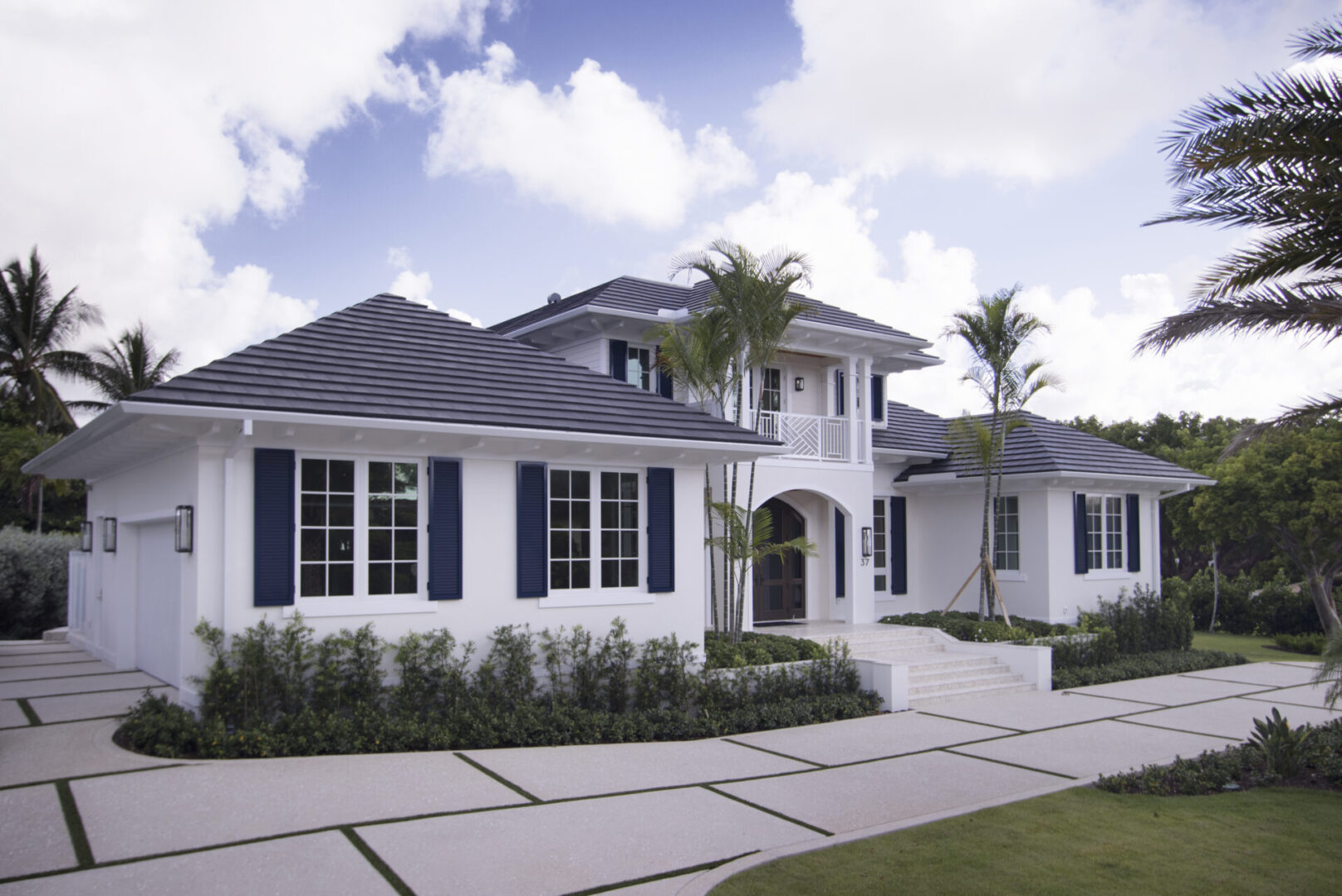 White house with black shutters and palm trees.