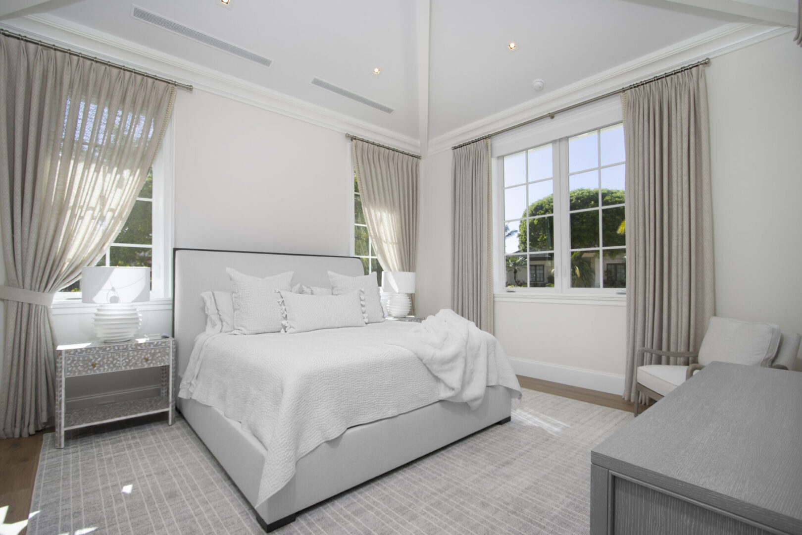 White bedroom with large windows and a bed.