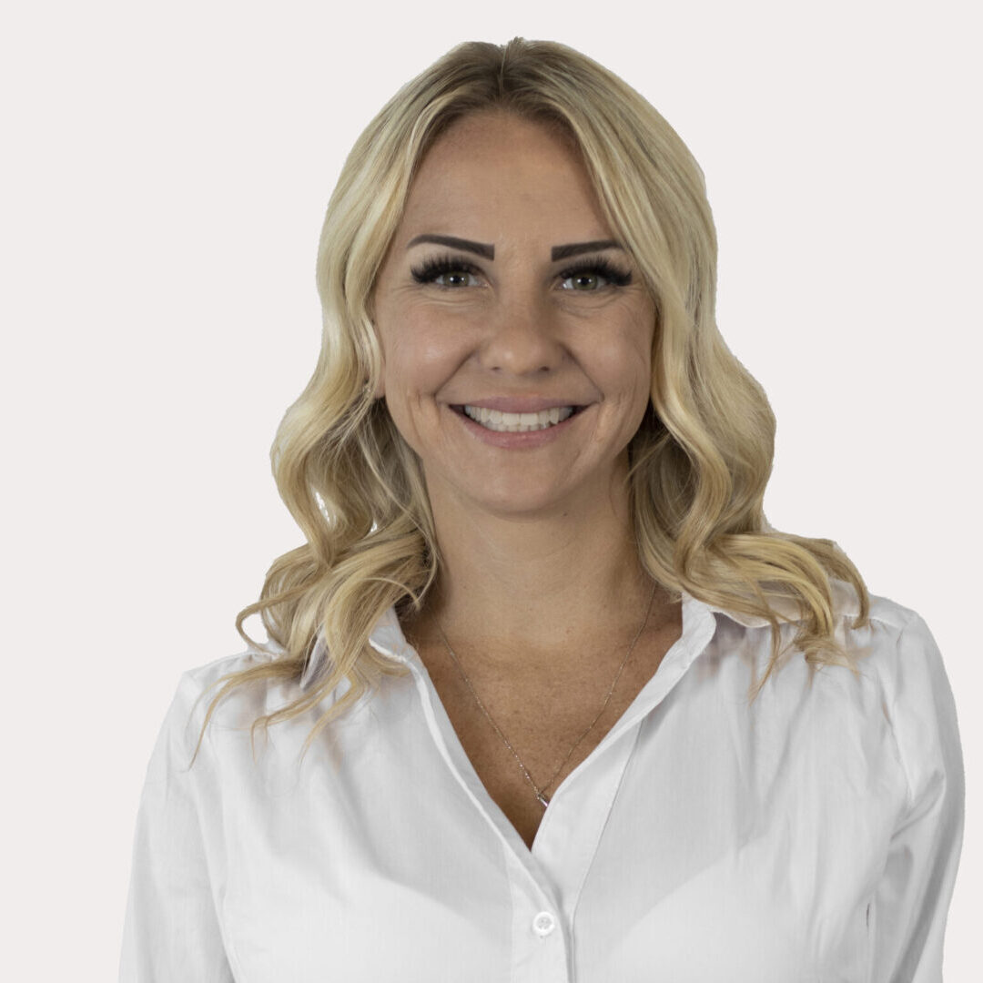 Smiling woman with blonde hair in a white shirt.