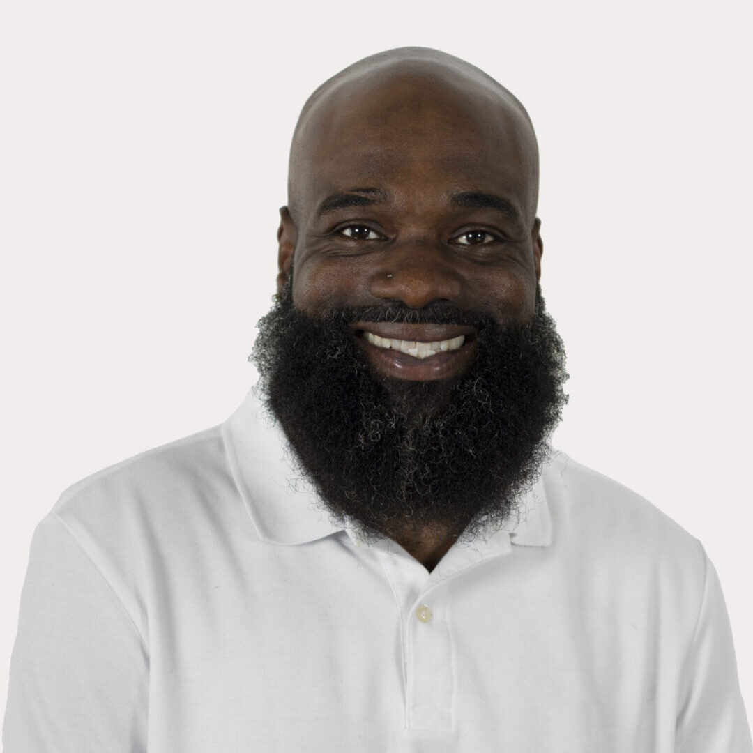 Smiling man with beard in white shirt.