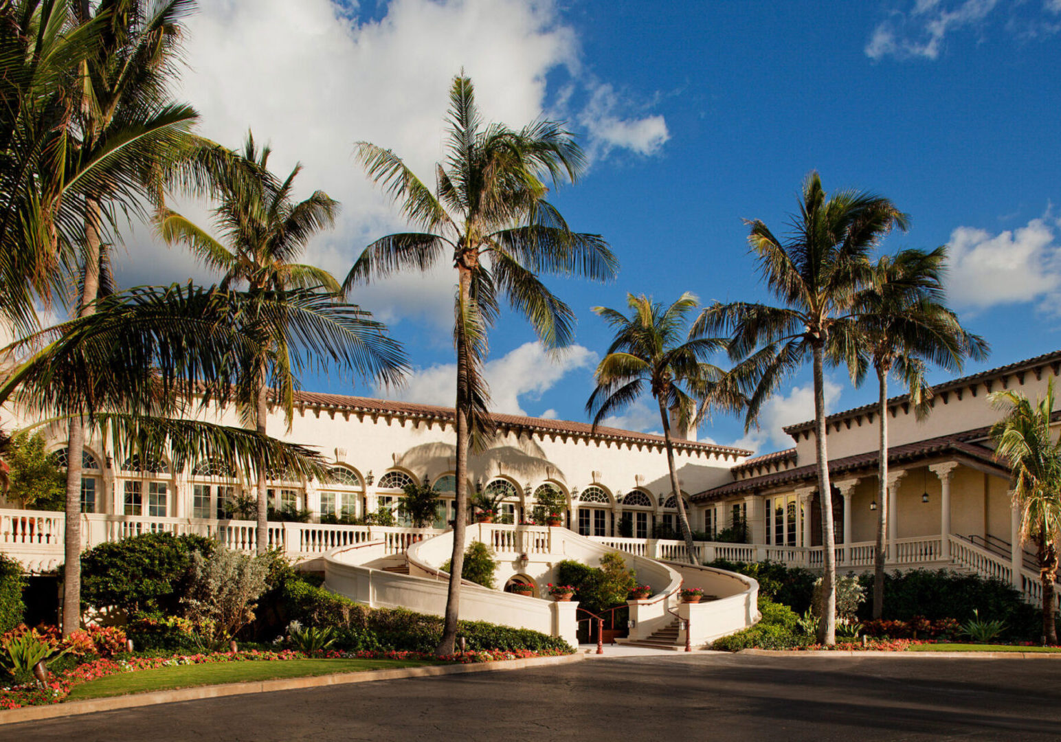 A large white building with palm trees in front of it.